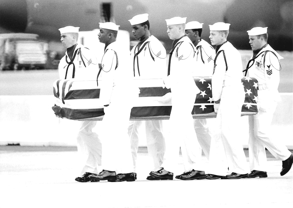 Honor Guard carrying one of the flag-draped coffins.